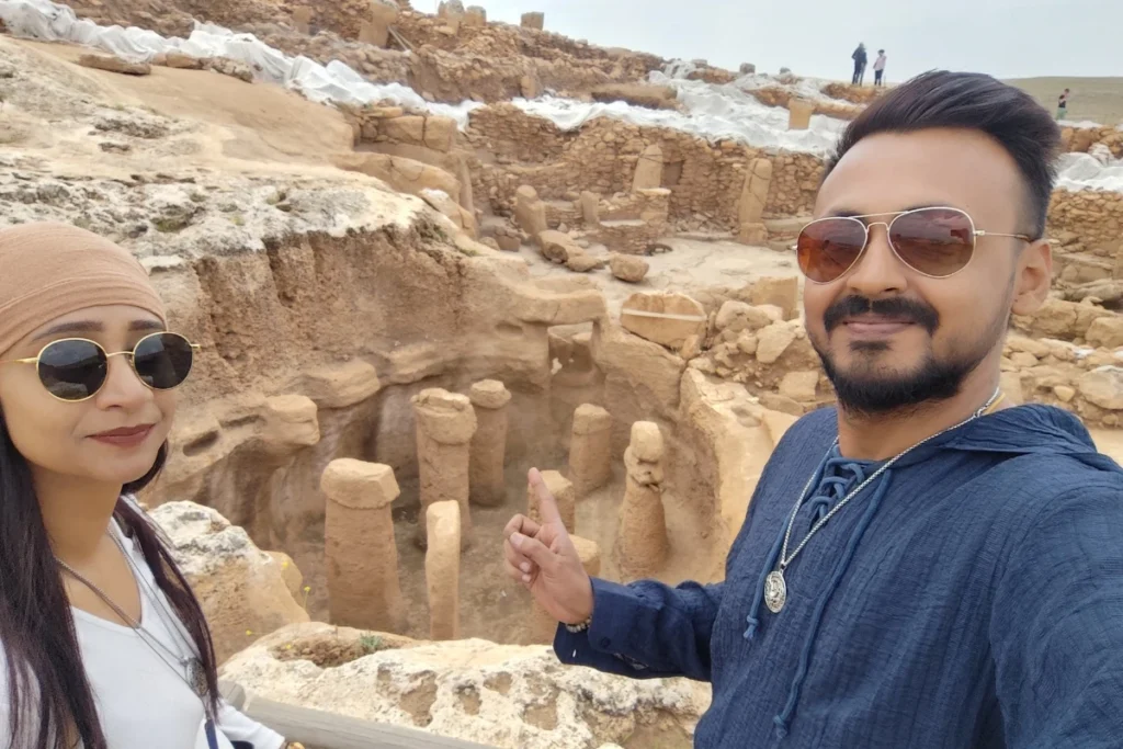Karahan Tepe 12 A selfie of Akash & Sumana smiling outdoors against a background of ancient ruins at the site.