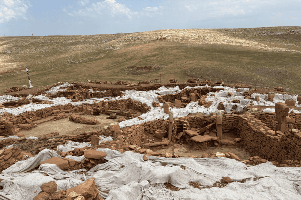 Karahan Tepe 15 A wide shot of multiple excavated stone pits and rock enclosures protected by white sandbags at the Karahan Tepe site.