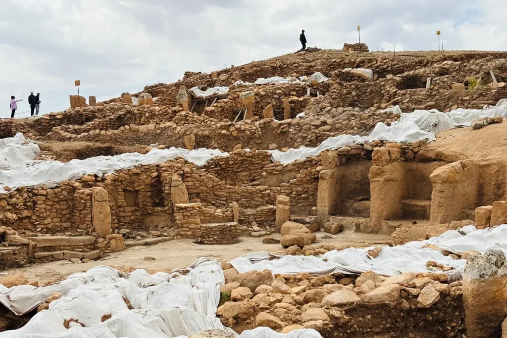 Karahan Tepe 5 A wide view of the Karahan Tepe archaeological excavation site spread across a dusty hill under a clear sky.