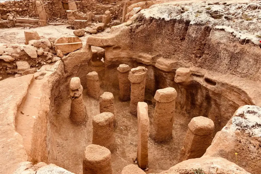 Karahan Tepe 7 Looking into the underground oval chamber featuring eleven upright, rounded stone pillars standing on the rock floor.