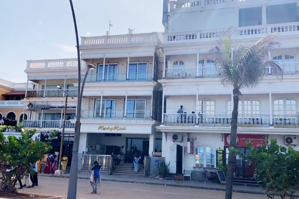 Pondicherry- French Colony A vibrant yellow and white colonial-style building with large arched windows and balconies.