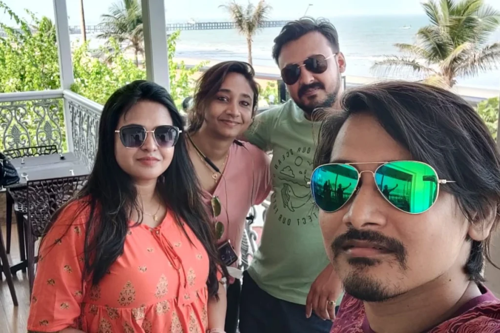 Pondicherry- Friends A group of four friends posing together outdoors under the sun, with one person in the foreground wearing green reflective sunglasses.