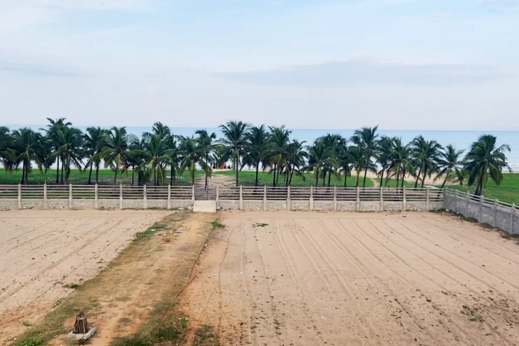 Pondicherry- Pranav Hotel -Sea View A fenced-in pathway leading toward the ocean, flanked by lines of trees on both sides.