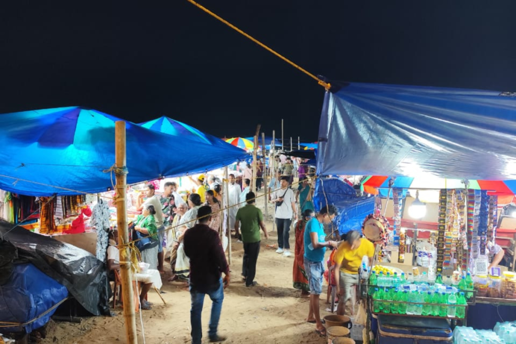 Puri Market A lively night scene at a local market with stalls selling toys and illuminated souvenirs under blue tarps.