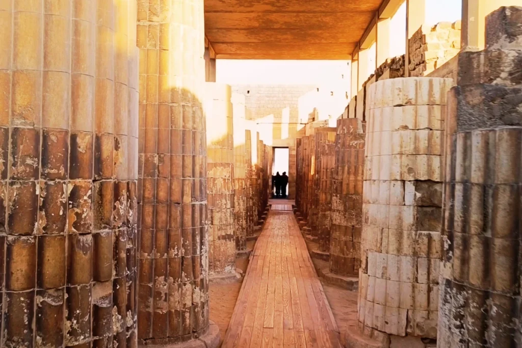 SAQQARA- 3 (2) A perspective view looking down a long, narrow corridor lined with monumental fluted stone pillars.
