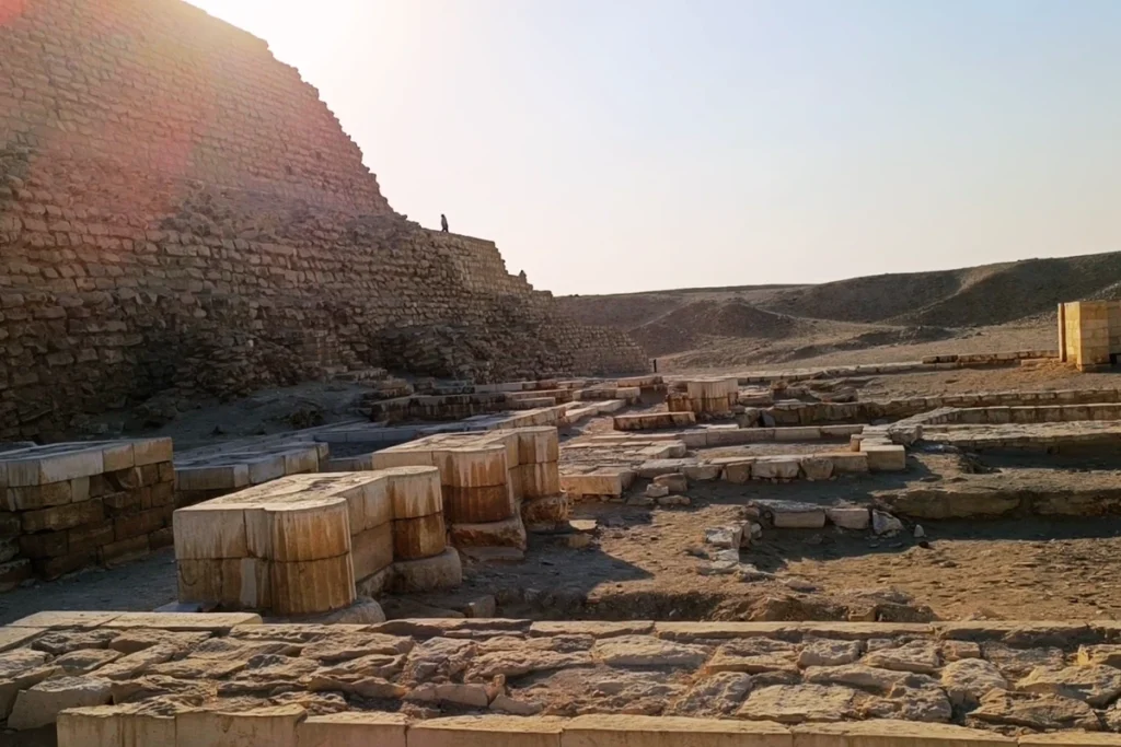 SAQQARA- 5 A daytime view showing the stone ruins, walls, and structures located at the rear base of the Step Pyramid.
