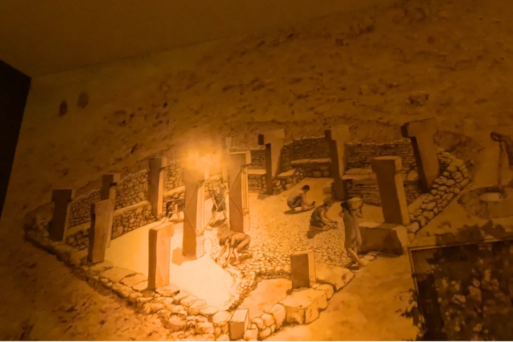 An artistic illustration showing early humans constructing and erecting the large T-shaped stone pillars at Göbekli Tepe.