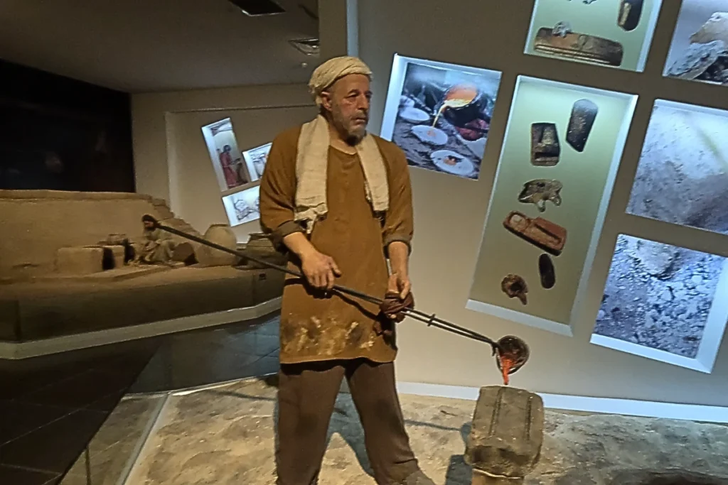 Life-sized mannequins in historic clothing displayed in a museum diorama representing human life during the Bronze Age.