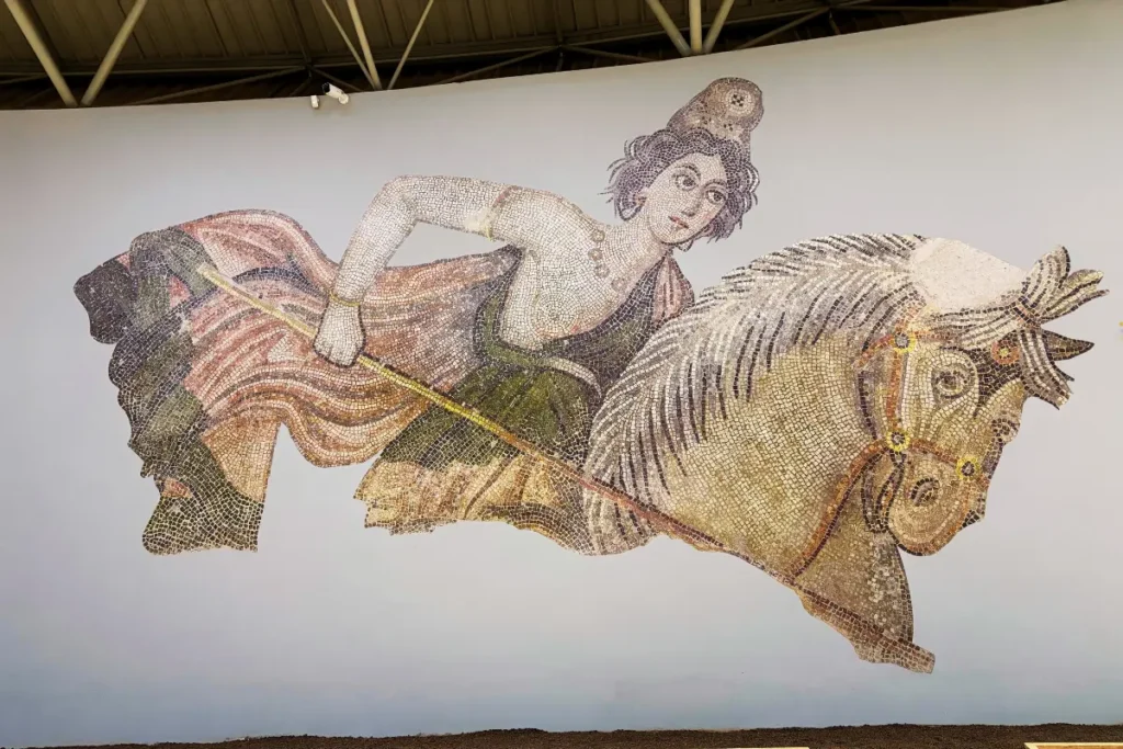 A detailed Roman floor mosaic depicting an Amazon queen warrior riding a horse during a hunt.