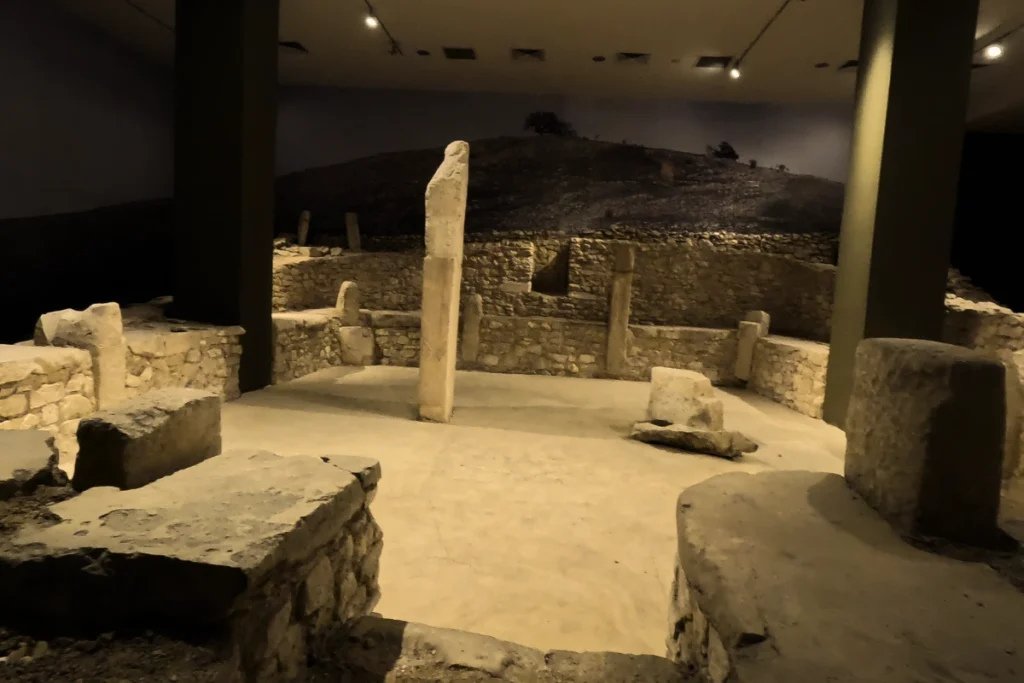 A reconstructed full temple room exhibit featuring original stone walls and pillars from the ancient Nevalı Çori site.