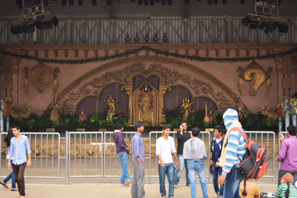 Tirupati- Balaji An ornate stone pillared hall or mandap with carvings and people moving through the structure.