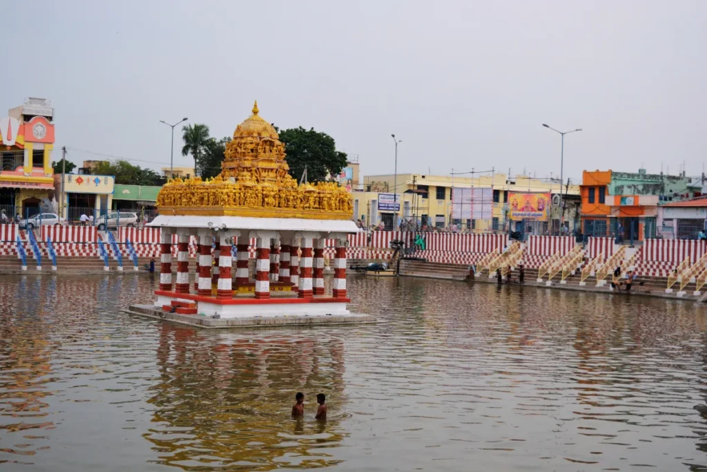 Tirupati- Lakshmi Temple A view across a calm, rectangular temple tank or stepwell reflecting an adjacent colorful temple complex.