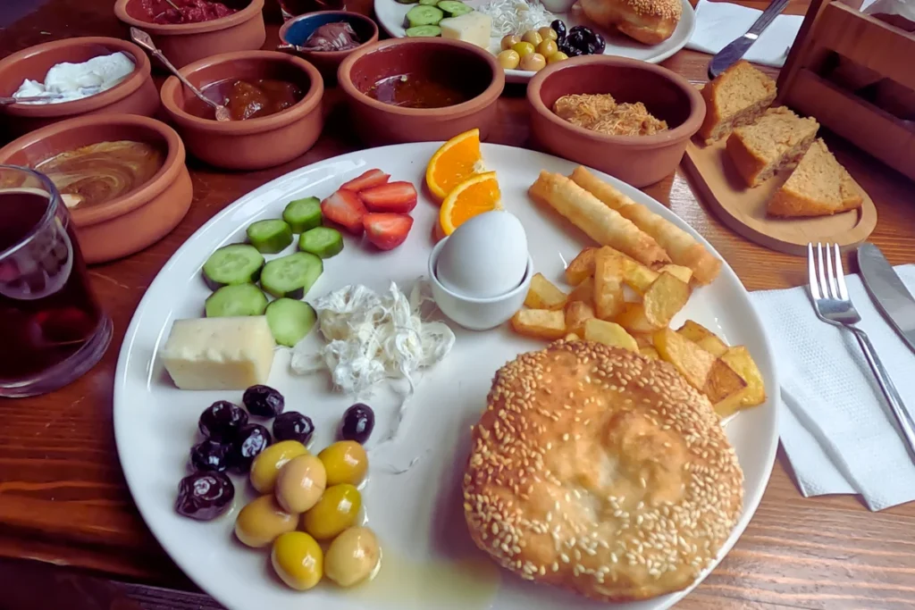 Turkish Breakfast 1 A close-up view of a hearty breakfast platter featuring bread, hard-boiled eggs, cheese, cucumber slices, and small side dishes.
