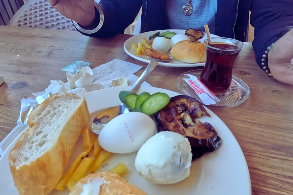 Turkish Breakfast 3 A plate with freshly sliced bread, boiled eggs, and cheese, accompanied by a glass of Turkish tea on a wooden table.