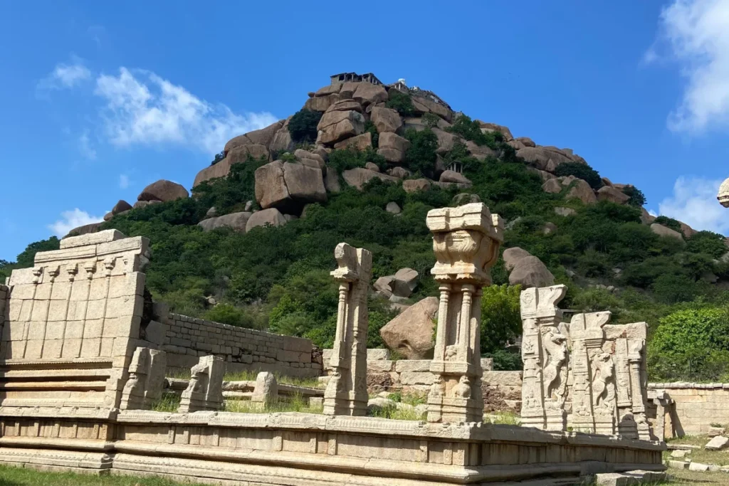 Achyutaraya Temple complex & Matanga Hill Looking up from stone temple ruins toward the steep, rocky peak of Matanga Hill rising under a clear sky.
