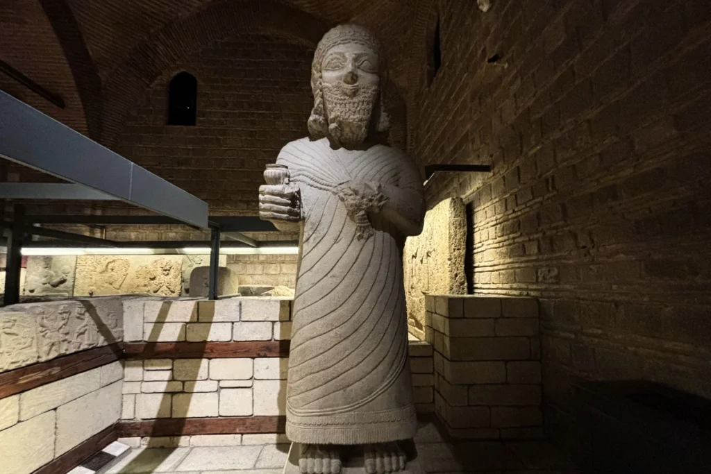 Anatolian Museum 13 A tall, ancient carved basalt statue of a Neo-Hittite king with a detailed beard and patterned robe displayed indoors under spotlighting.