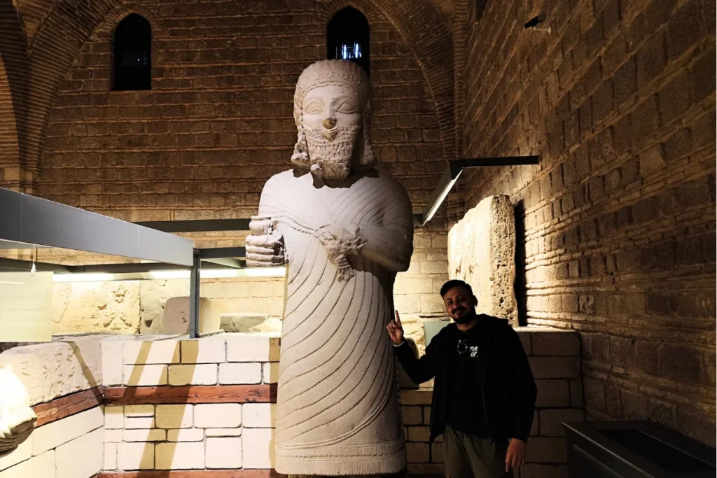 Anatolian Museum 16 Akash standing next to and posing beside the colossal ancient stone statue of King Mutallu inside the museum hall.