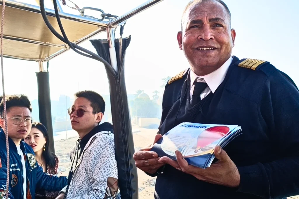 Egypt- Hot Air Balloon 7 A smiling hot air balloon pilot handing flight completion certificates to passengers.