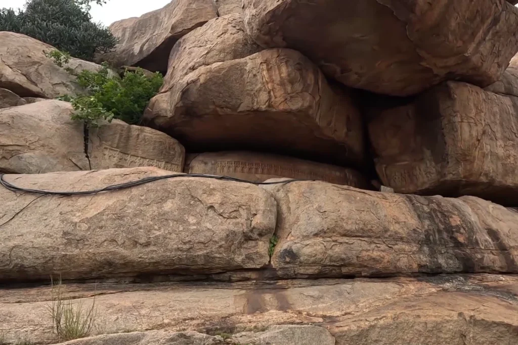 Hampi River side (1) Close-up of ancient stone carvings and miniature bas-relief figures etched directly into the bedrock near the river edge.
