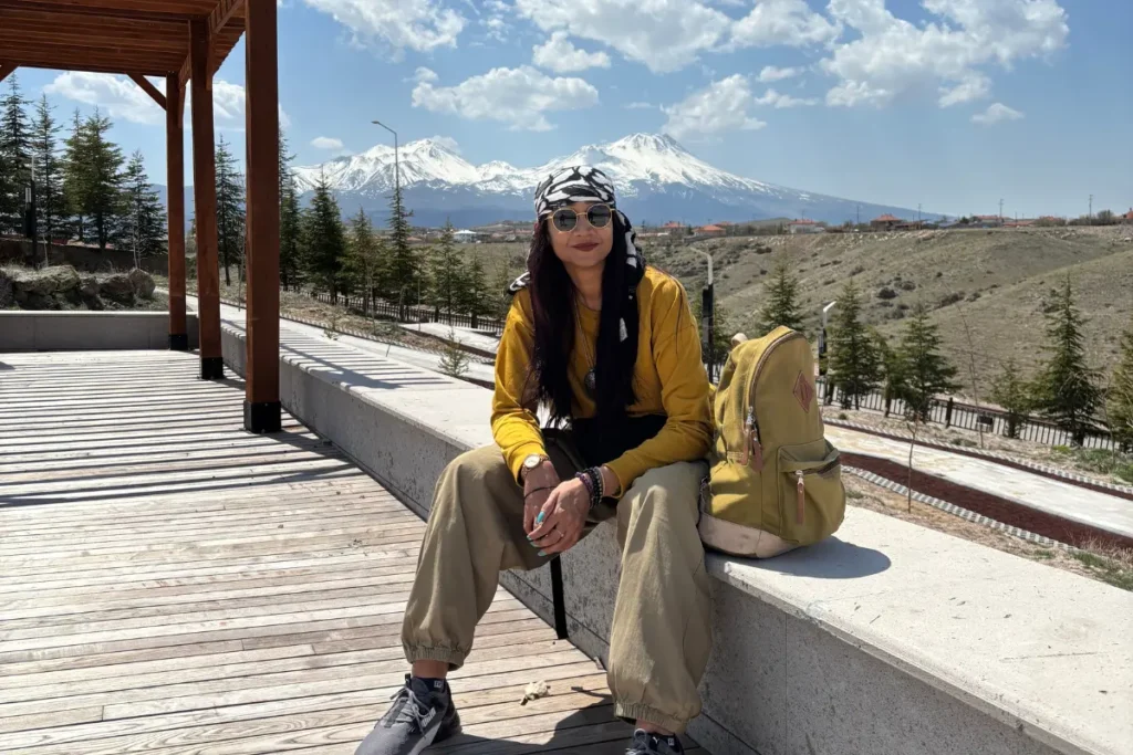 Ihlara Valley 2 Sumana sitting on a wooden bench at a viewpoint overlooking the expansive Ihlara Valley canyon.