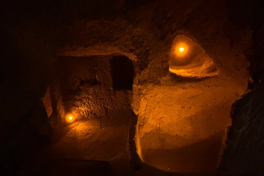 KAYMAKLI 1 A small chamber carved out of volcanic tuff rock with warm orange accent lights highlighting subterranean architecture.