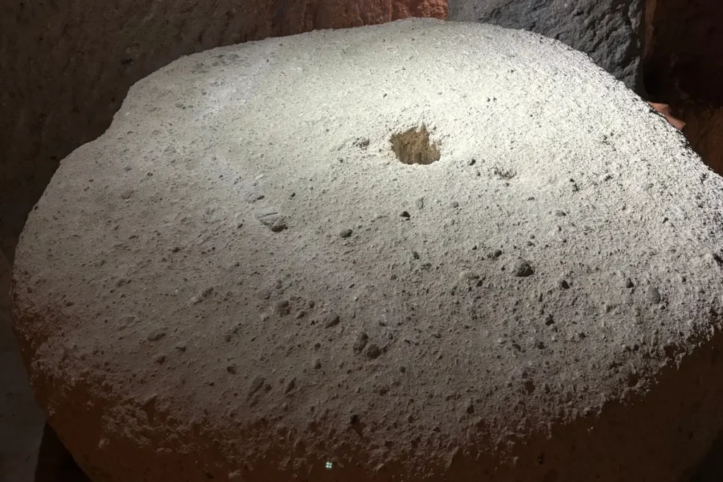 KAYMAKLI 3 A large, circular millstone-like rolling defense door carved from volcanic tuff with a central viewing/spear hole used to seal passages.