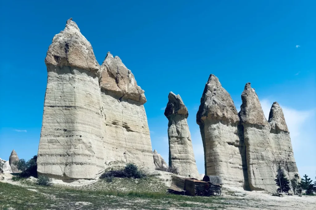 Love Valley 1 A scenic view of tall, slender fairy chimney formations rising from the valley floor under a clear sky.