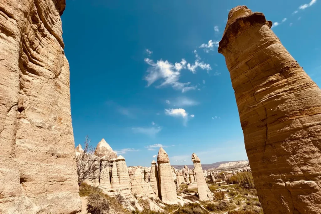 Love Valley 2 Tall, phallic-shaped rock spires and fairy chimneys standing prominently under a bright blue sky in Love Valley.