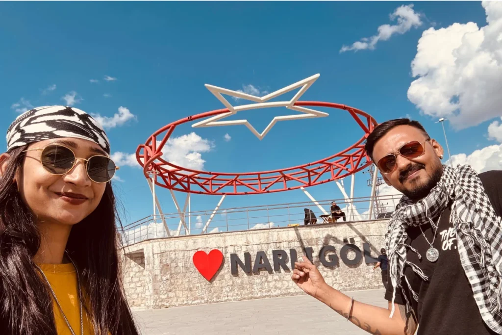Narligol 1 Akash & Sumana taking a selfie in front of a red heart-shaped "Narlıgöl" photo frame sign with the crater lake in the background.