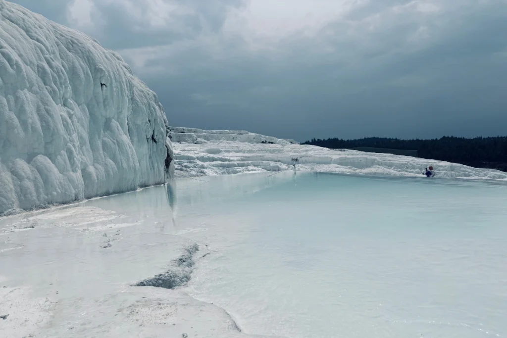 PAMUKKALE (1) A broad landscape view of the stark white, frozen-waterfall-like calcium cliffs and thermal pools at Pamukkale.
