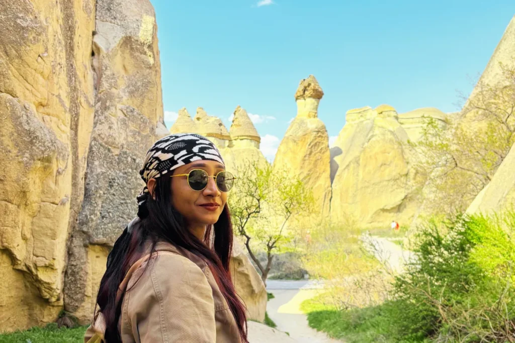 Pasabag Valley 1 A portrait of Sumana wearing sunglasses and a patterned scarf, posing in front of the iconic fairy chimneys at Paşabağı.