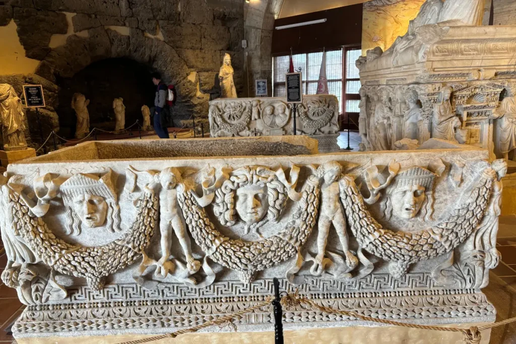 The Hierapolis Archaeological Museum 1 An indoor museum display featuring intricately carved Roman marble sarcophagi with relief sculptures inside an ancient vaulted stone room.