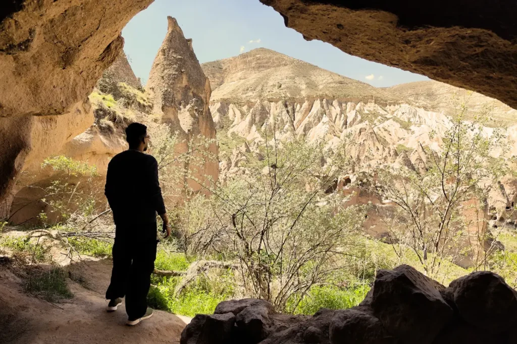 ZELVE VIEW A view looking out from inside a rock cave onto the dramatic canyon cliffs and rock-cut structures of Zelve.