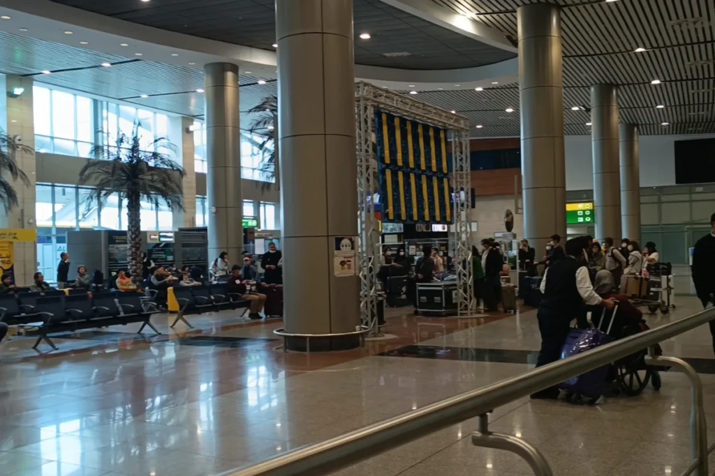 CAIRO Airport 2 Indoor view of a modern terminal terminal inside Cairo International Airport showing passengers walking with luggage past a tall golden Egyptian statue.