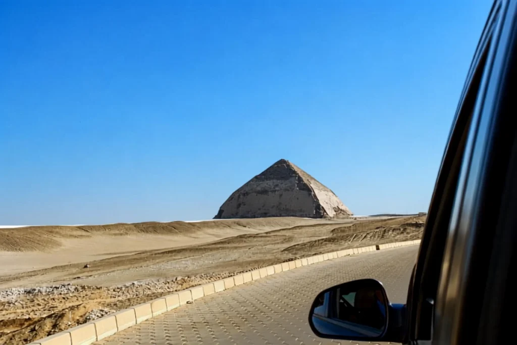 EGYPT -BENT PYRAMID View of the Red Pyramid in the distance across a flat desert landscape, visible through the side window of a vehicle.