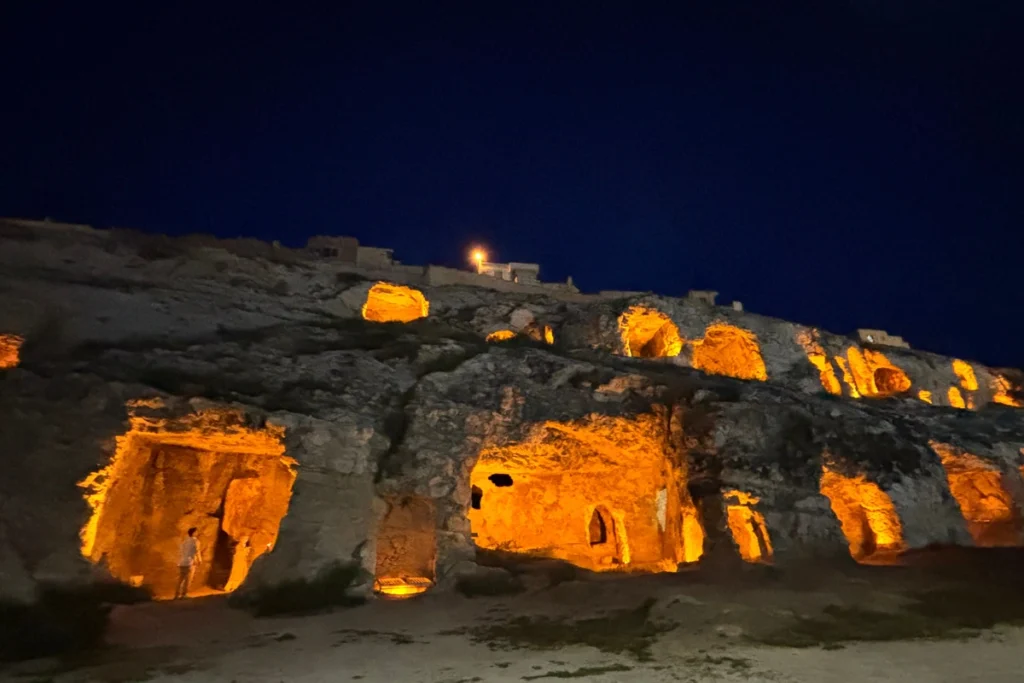 Kızılkoyun Necropolis 3 Close-up view of multiple illuminated cave openings and rock tomb entrances set into the craggy cliff face.