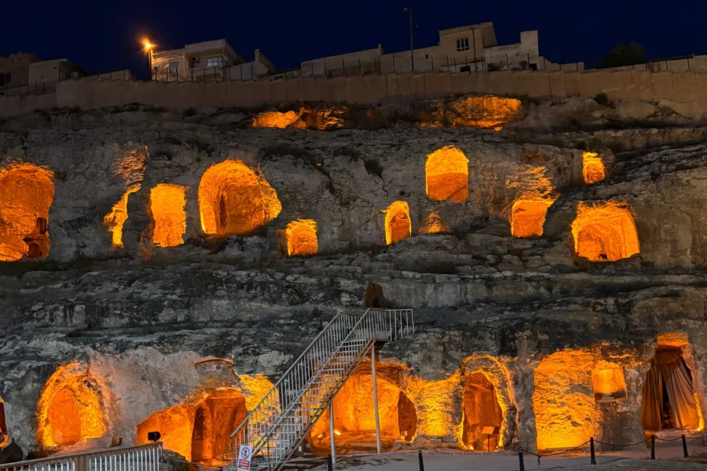 Kızılkoyun Necropolis 4 Nighttime shot of a metal staircase leading up to the lower tier of illuminated ancient rock tombs embedded in the hillside complex.