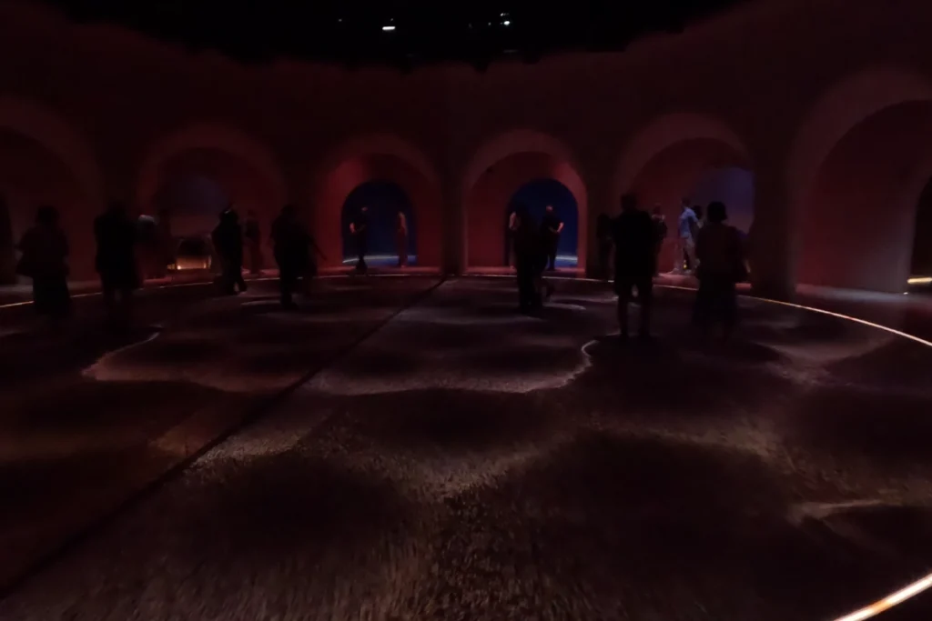 Museum of the future 5 Visitors relaxing inside a dimly lit sanctuary dome with futuristic overhead lighting projection at the Al Waha wellness exhibit.