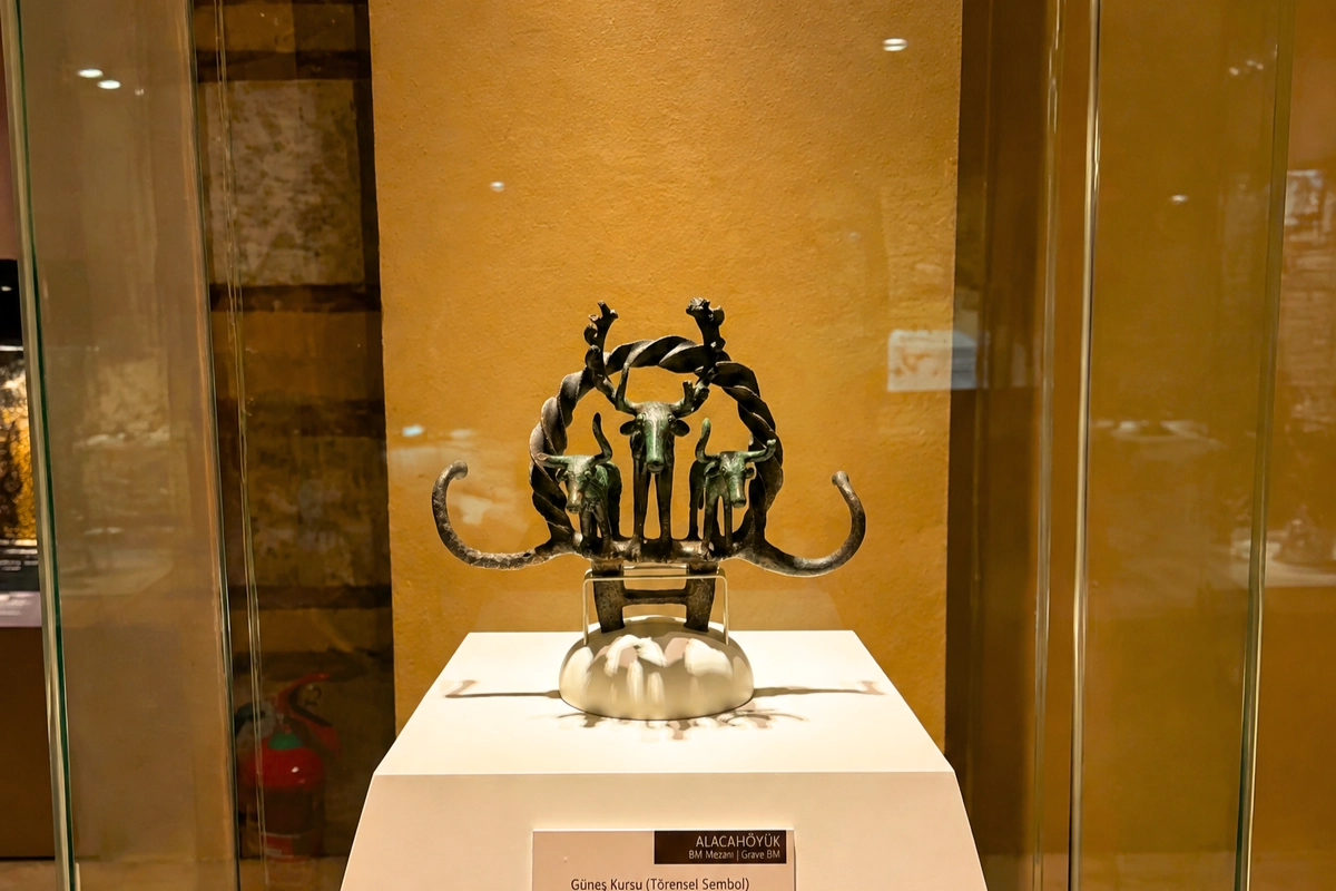 Close-up of an intricate bronze ceremonial standard featuring bull and deer symbols displayed inside a glass case at the Museum of Anatolian Civilizations.