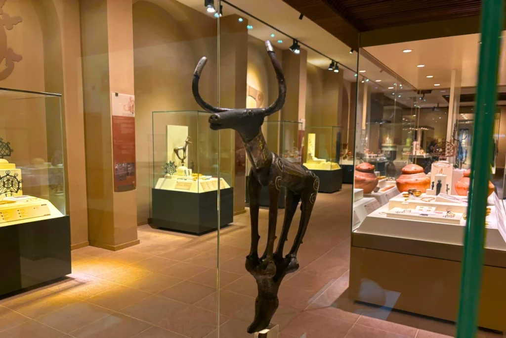 Alacahoyuk 3 Ancient bronze animal statuettes and ritual objects displayed on glass shelves inside a museum showcase.