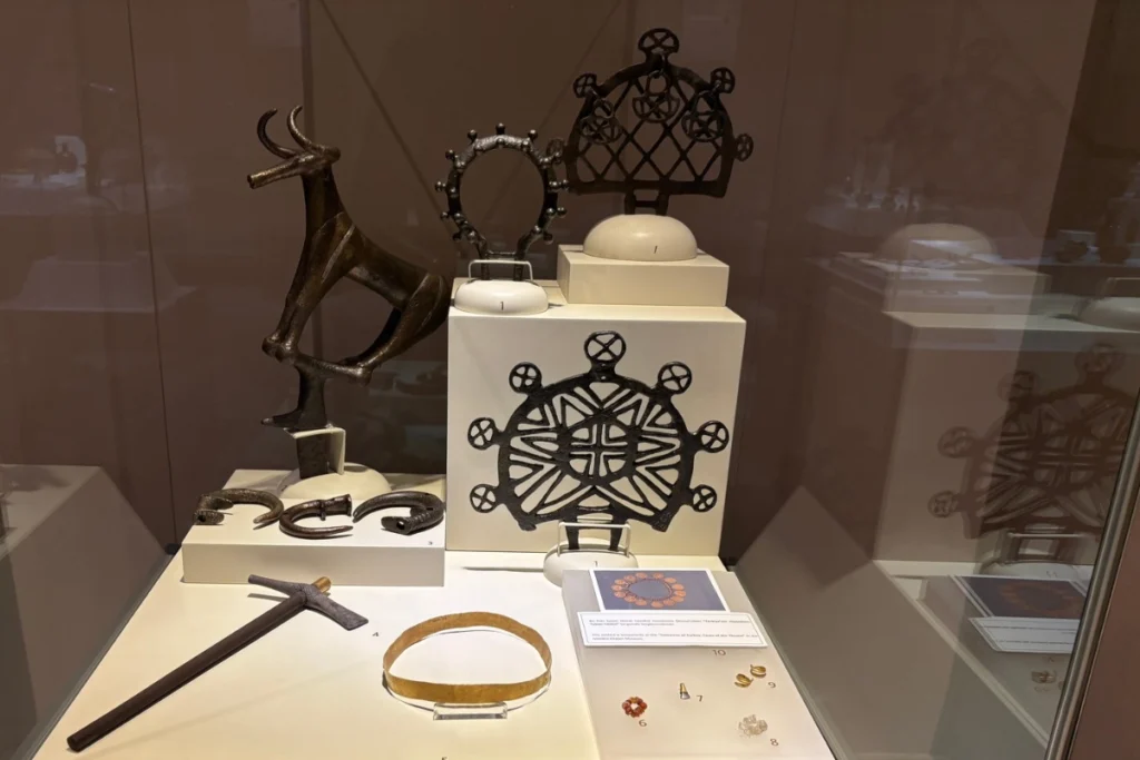 Alacahoyuk 8 Museum shelf displaying various ancient sun disks, metallic jewelry, and ritual artifacts.