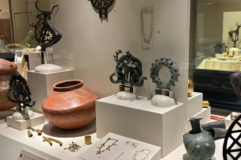 Alacahoyuk 9 Museum exhibit featuring prehistoric pottery vessels alongside metal animal statuettes and jewelry.