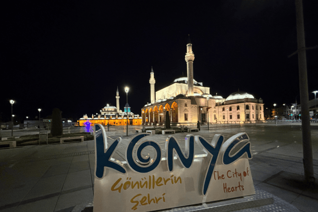 CatalHoyuk 16 Nighttime view of Mevlana Square in Konya with an illuminated "Konya" sign and glowing mosque towers in the background.