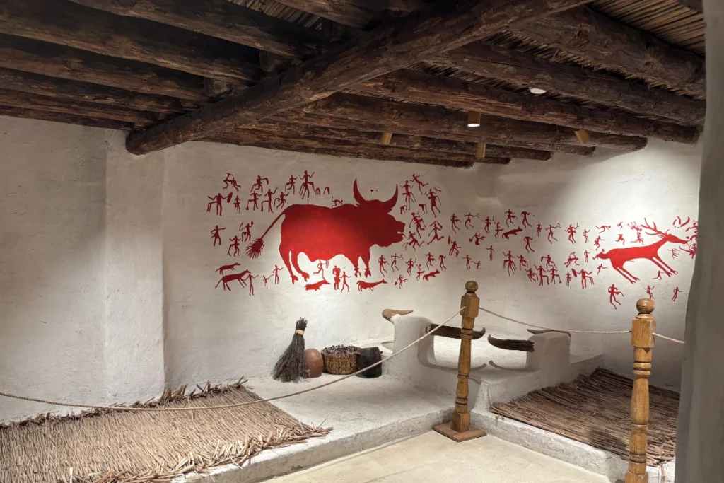 CatalHoyuk 3 Museum display showcasing bull horns and painted wall murals from an excavation site interior.