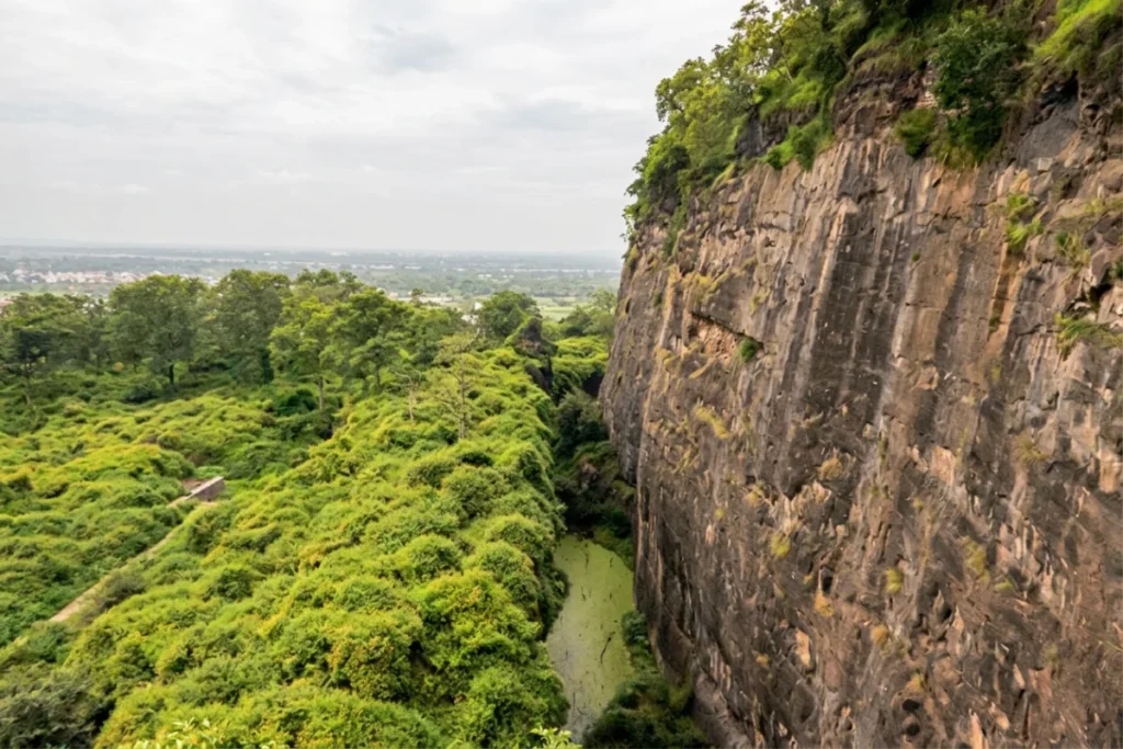 Daulatabad Fort 4 Deep, vertical rock-cut moat surrounding the fort walls with green vegetation growing along the edges.