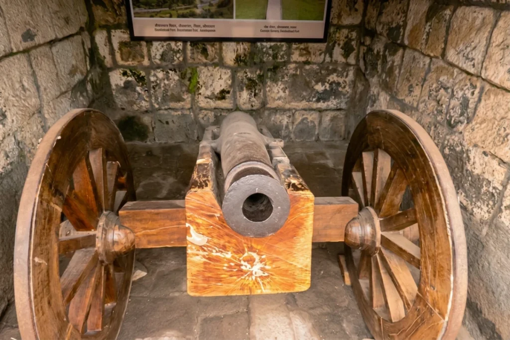 Daulatabad Fort 8 Close-up of a historical cannon mounted on large wooden wheels with iron rims inside the fort grounds.