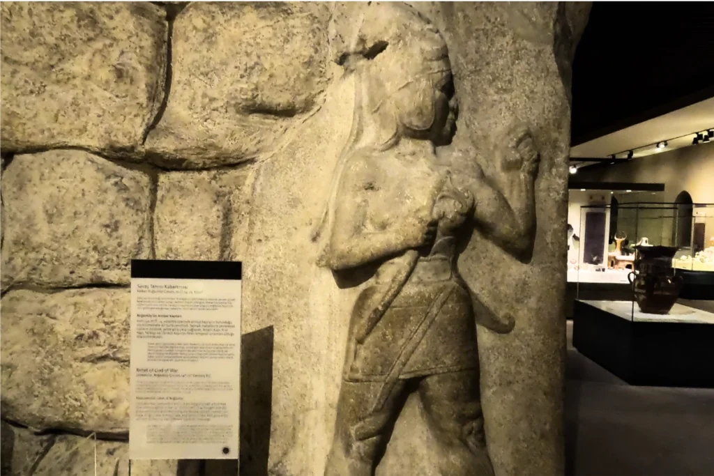 Detailed museum exhibition highlighting the weapon and clothing details of the Hittite warrior.
