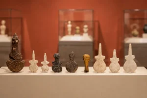 A lineup of ancient stylized Anatolian marble, alabaster, and stone idols displayed in a row inside a museum showcase.