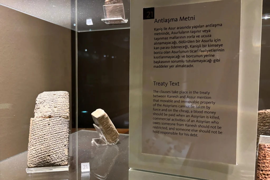 Kultepe Tablet 5 Ancient cuneiform clay tablets and an informational display plaque titled "Treaty Text" inside a glass museum showcase, explaining the terms of the Kanesh-Assur treaty.