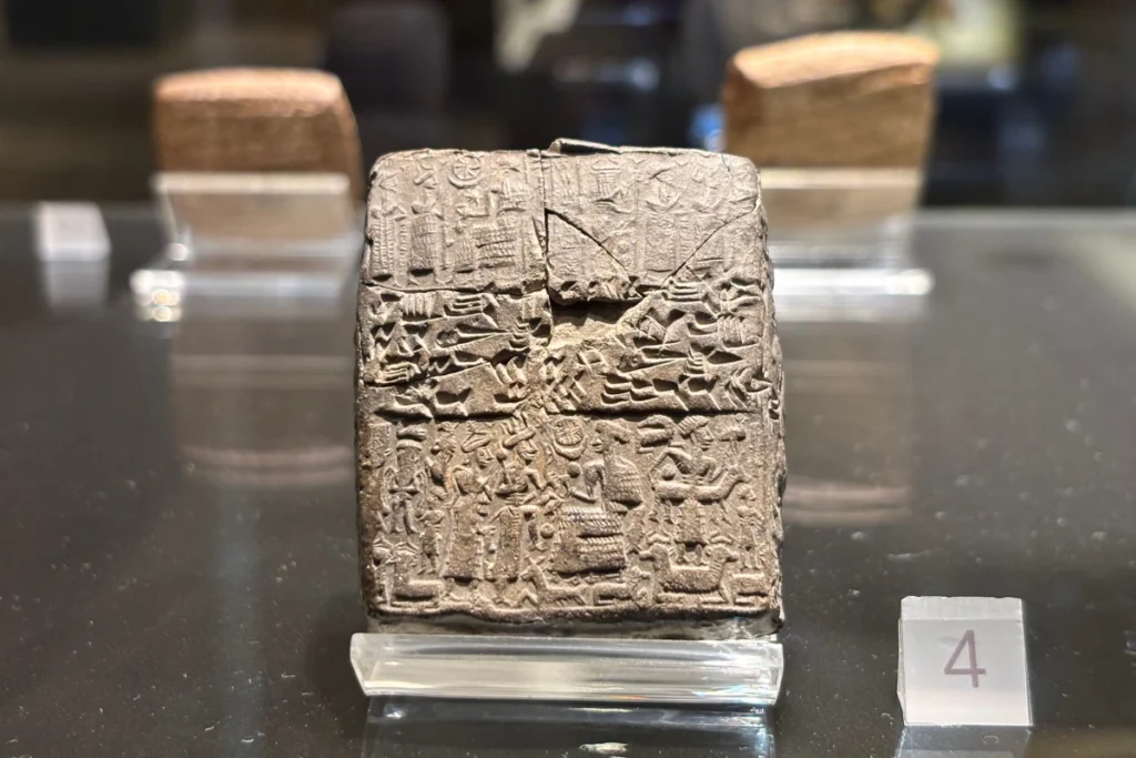 Kultepe Tablet 6 Close-up of an ancient, rectangular clay tablet inscribed with detailed cuneiform writing and carved seal impressions, displayed upright inside a museum display case with the caption "VERDICT OF KANESH" beneath it.